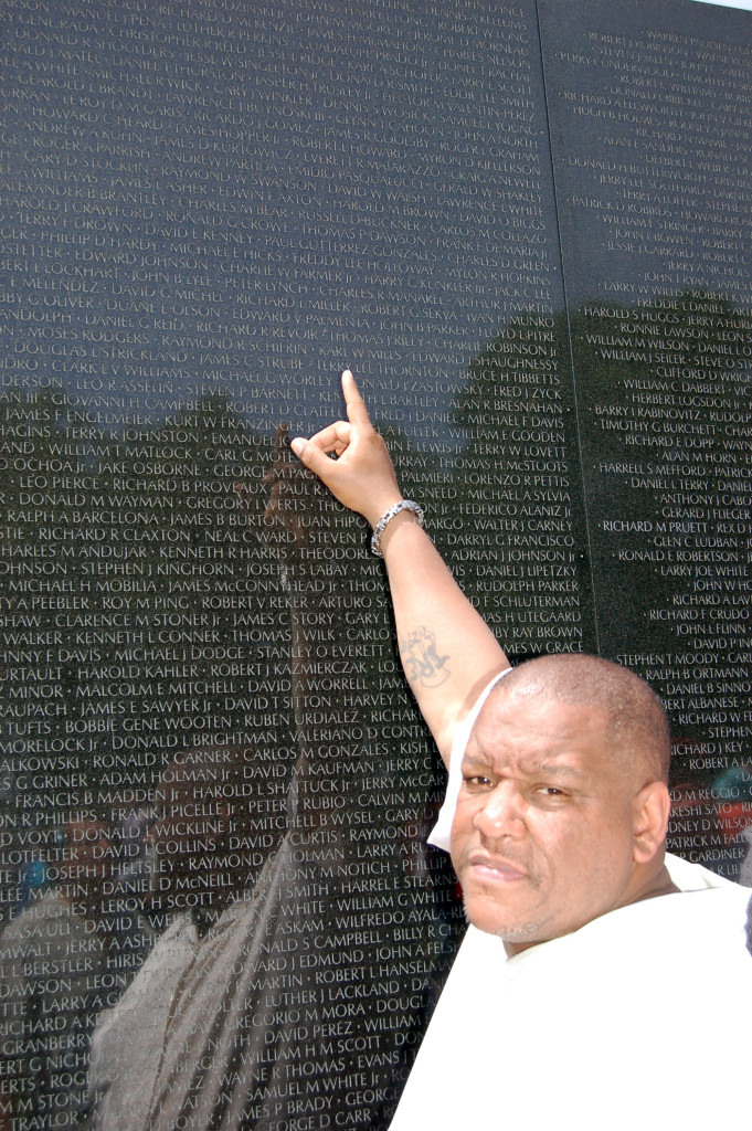 Robert Howard II point ing to father's name on The Wall